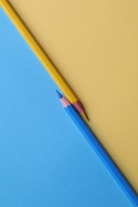 Close-up of vibrant yellow and blue colored pencils on contrasting paper backgrounds.